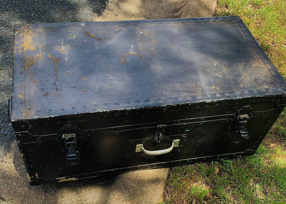 Black travel trunk sitting on cement curb